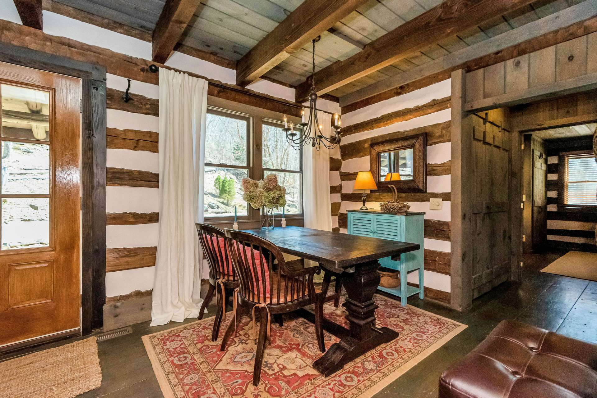 The dining area is positioned to allow for easy flow between the kitchen and living spaces. A sturdy wooden table serves as the focal point, its surface weathered with character, inviting inhabitants and guests to gather around for shared meals and conversations.