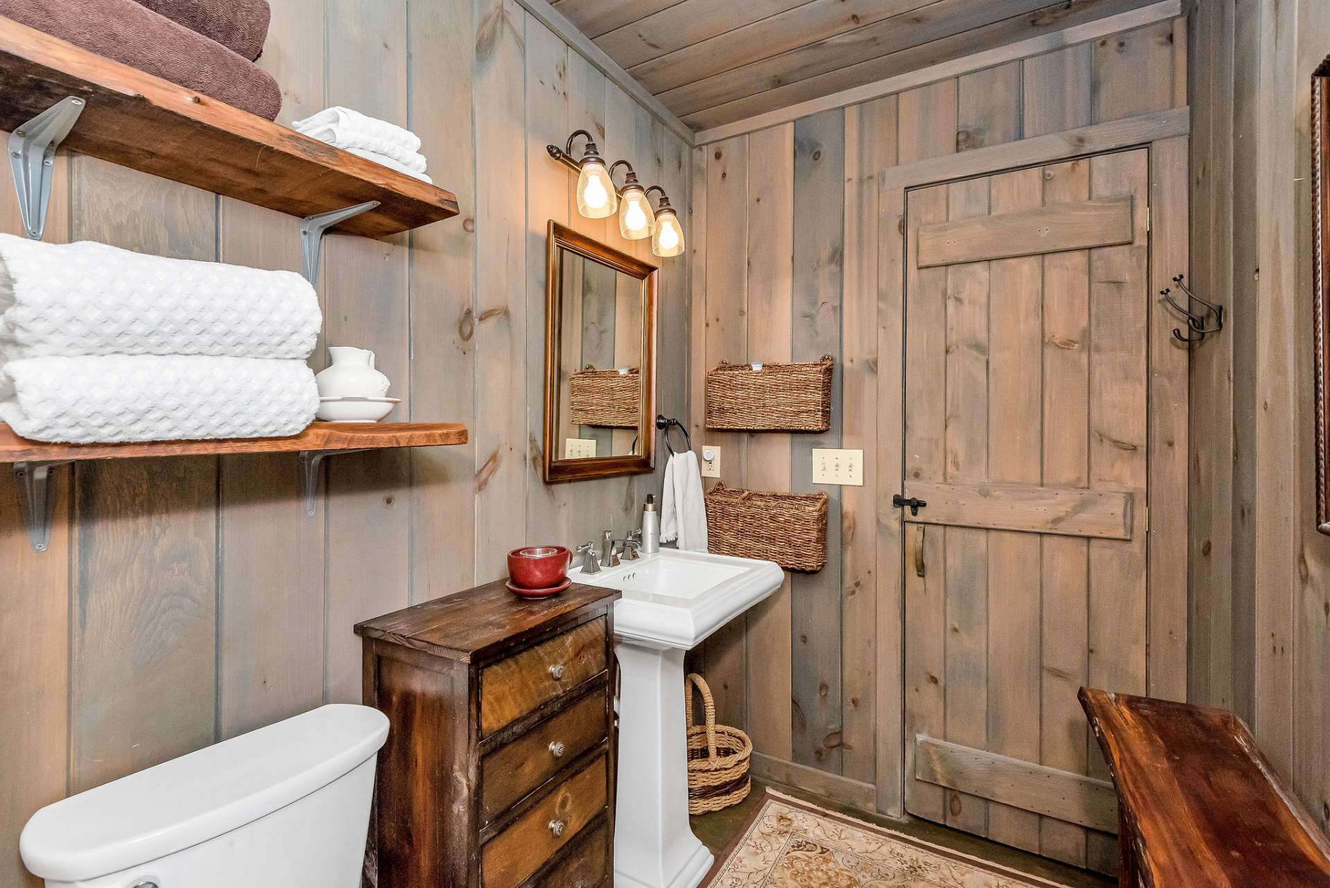 To enhance the rustic ambiance of the space, a couple of carefully selected rustic furniture pieces adorn the bathroom adding warmth and character to the room while providing some additional storage.