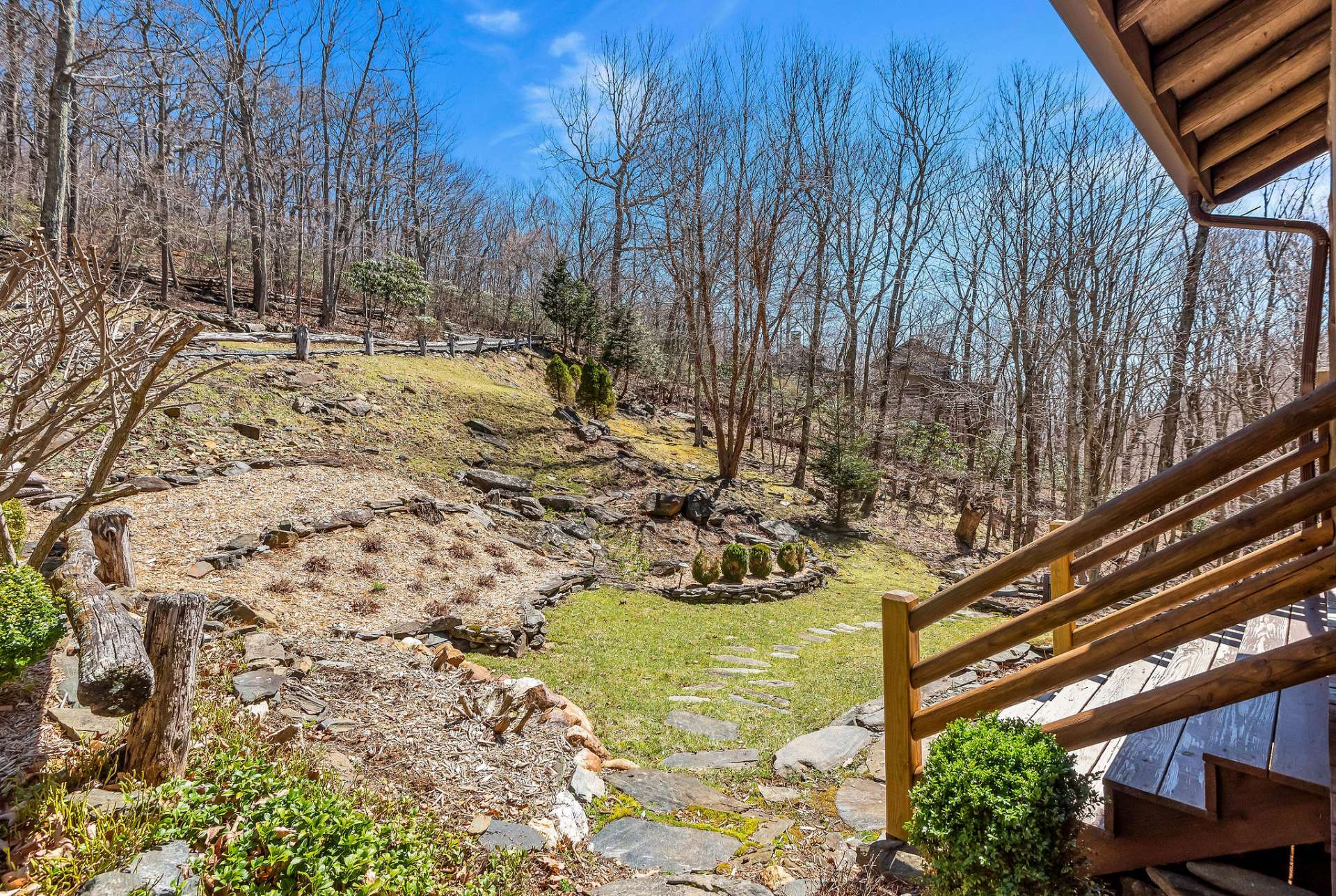 This cabin's naturally landscaped areas, adorned with native stone, will be full of blooming flowers and shrubs soon.