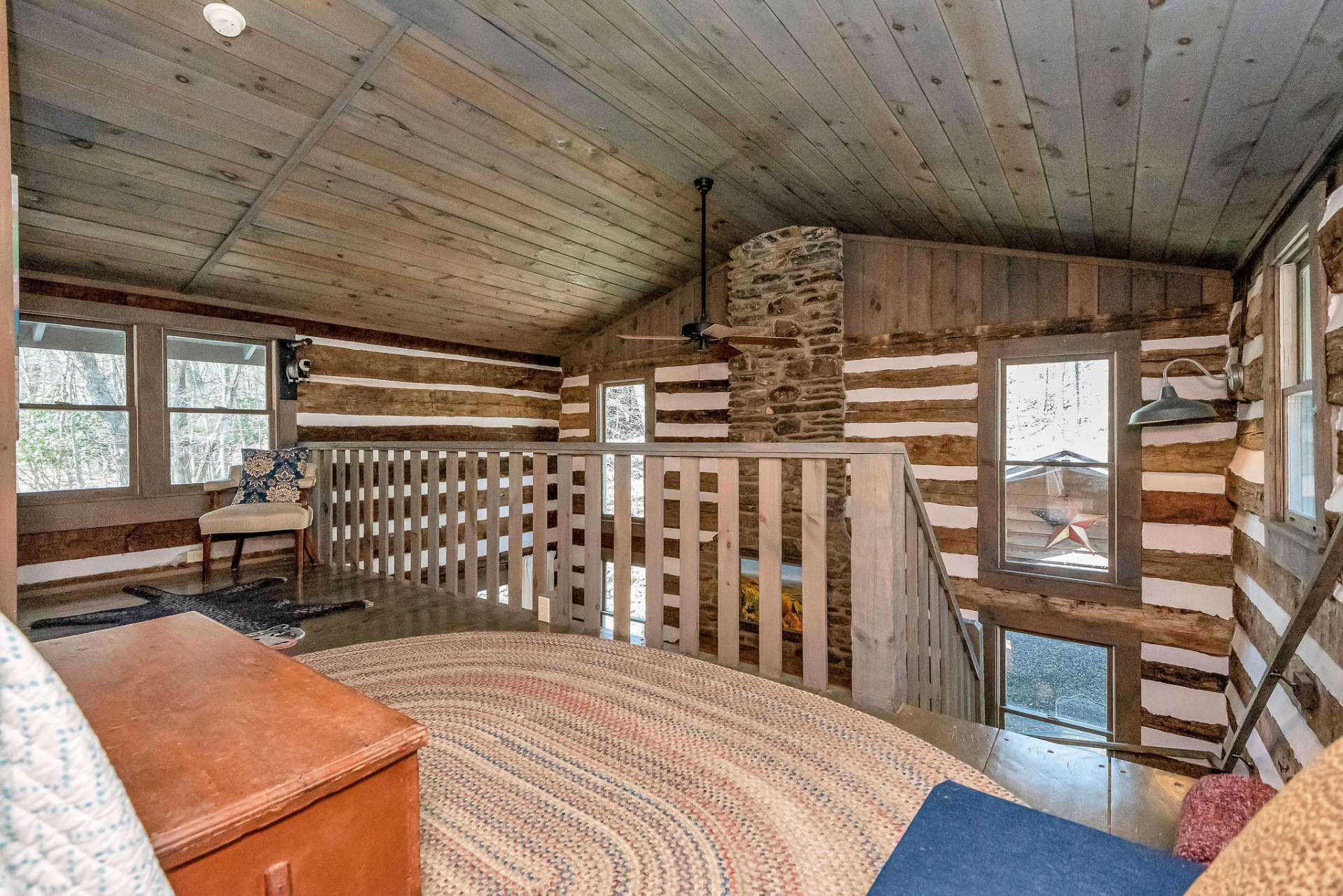 Positioned above the main living area, it offers a view of the stone fireplace and living area below. From this vantage point, occupants can enjoy the flickering warmth of the fire and the rustic ambiance of the living space
