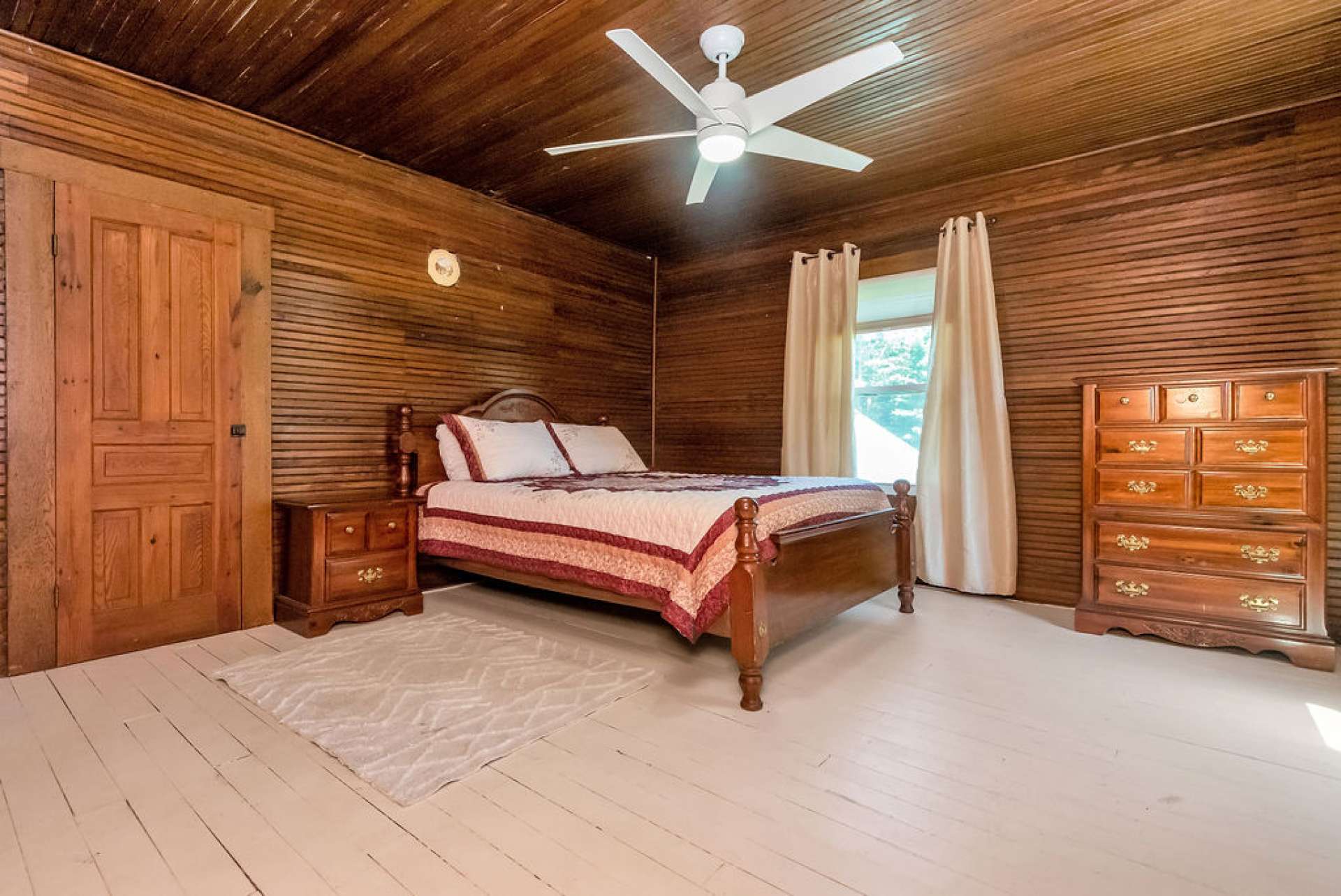 The fourth bedroom has painted floors for a different style. The color compliments the dark wood.