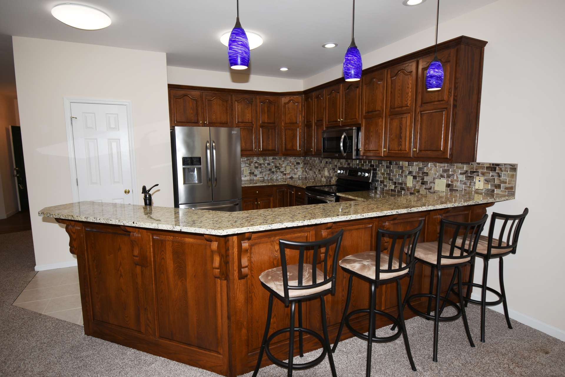 The well appointed and efficient kitchen offers stainless appliances, granite counter tops, and plenty of work and storage space including a pantry and a bar with seating.