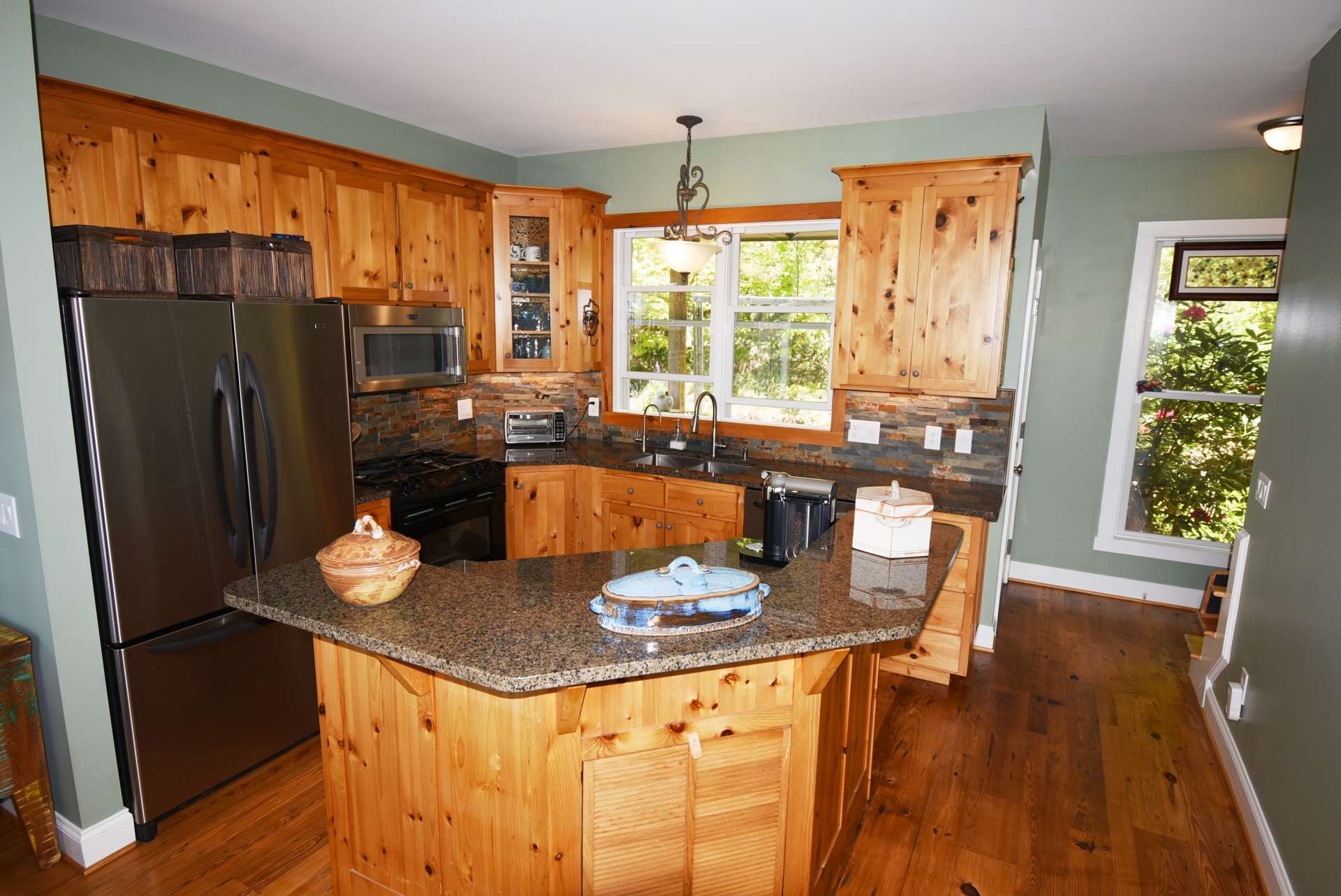The cozy space saving kitchen features custom cabinetry, stainless appliances, a center work island with casual dining area and ample storage space. The kitchen also has access to a covered porch to relax with morning's first cup of coffee.