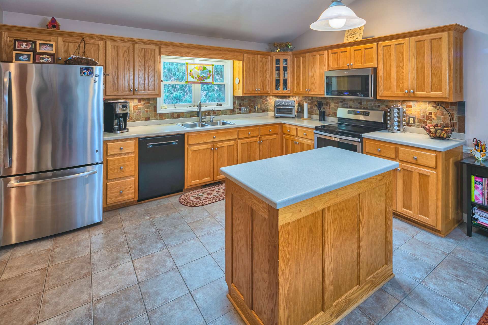 The kitchen also offers plenty of work and storage space with solid surface countertops, a center island, and ceramic tile flooring.