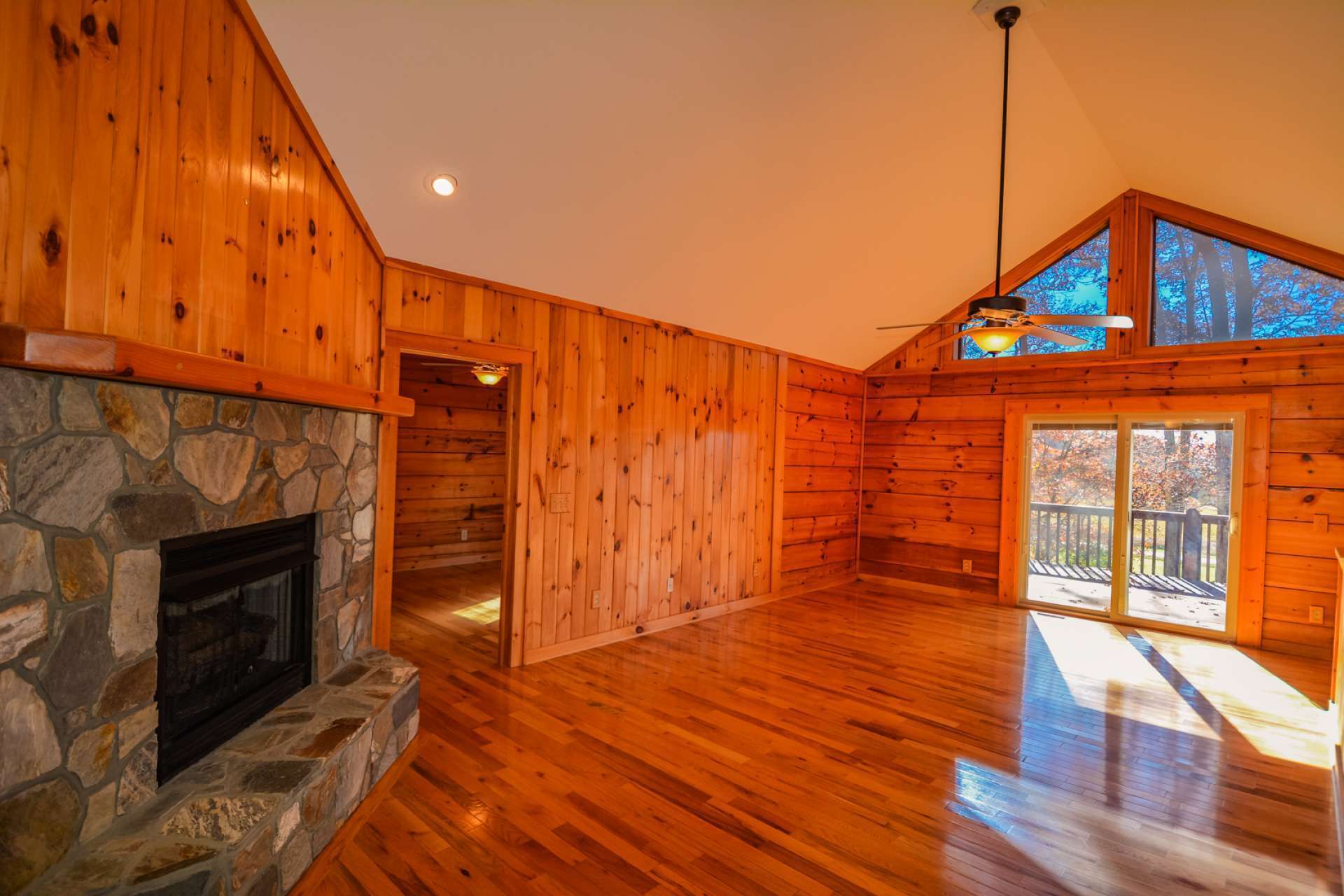 The vaulted great room's focal points are the stone gas log fireplace and a wall of windows to take in the lush mountain setting. Gleaming wood floors compliment the vaulted ceiling and wood walls.