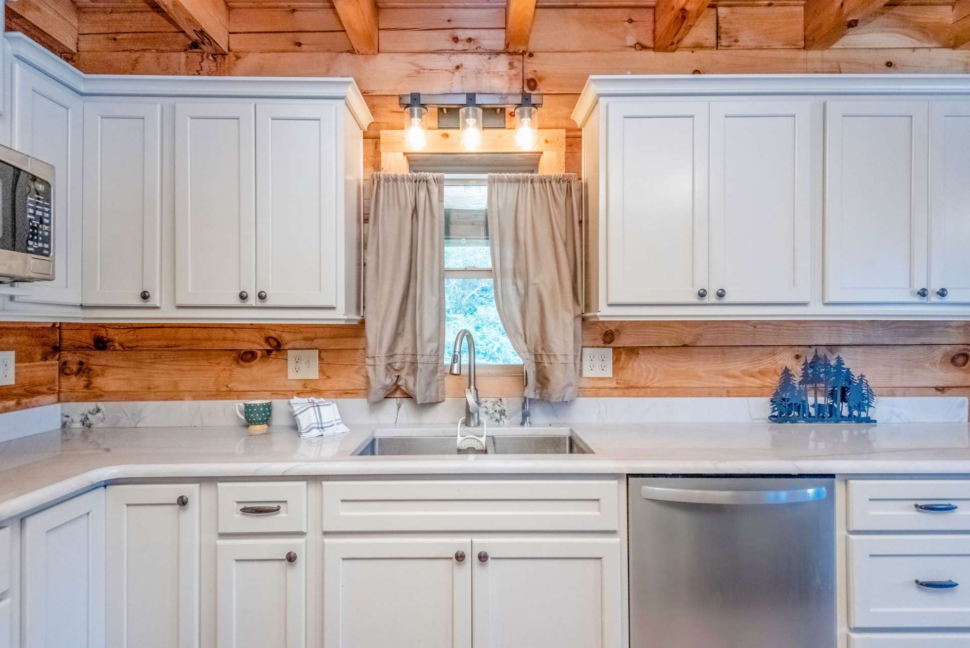 Farmhouse sink, stainless appliances, and intriguing lightening are all part of the charm of this kitchen.
