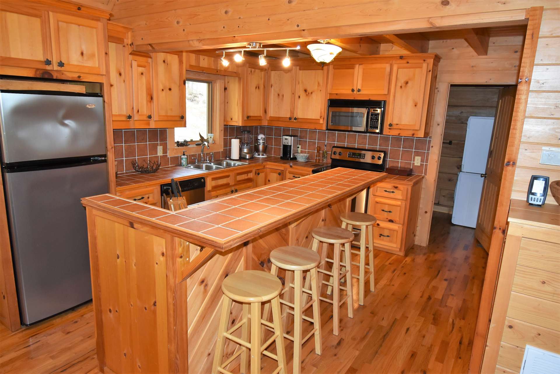 Open to the living and dining areas, this efficient log cabin kitchen offers ample work and storage space that includes a bar with seating for informal dining.