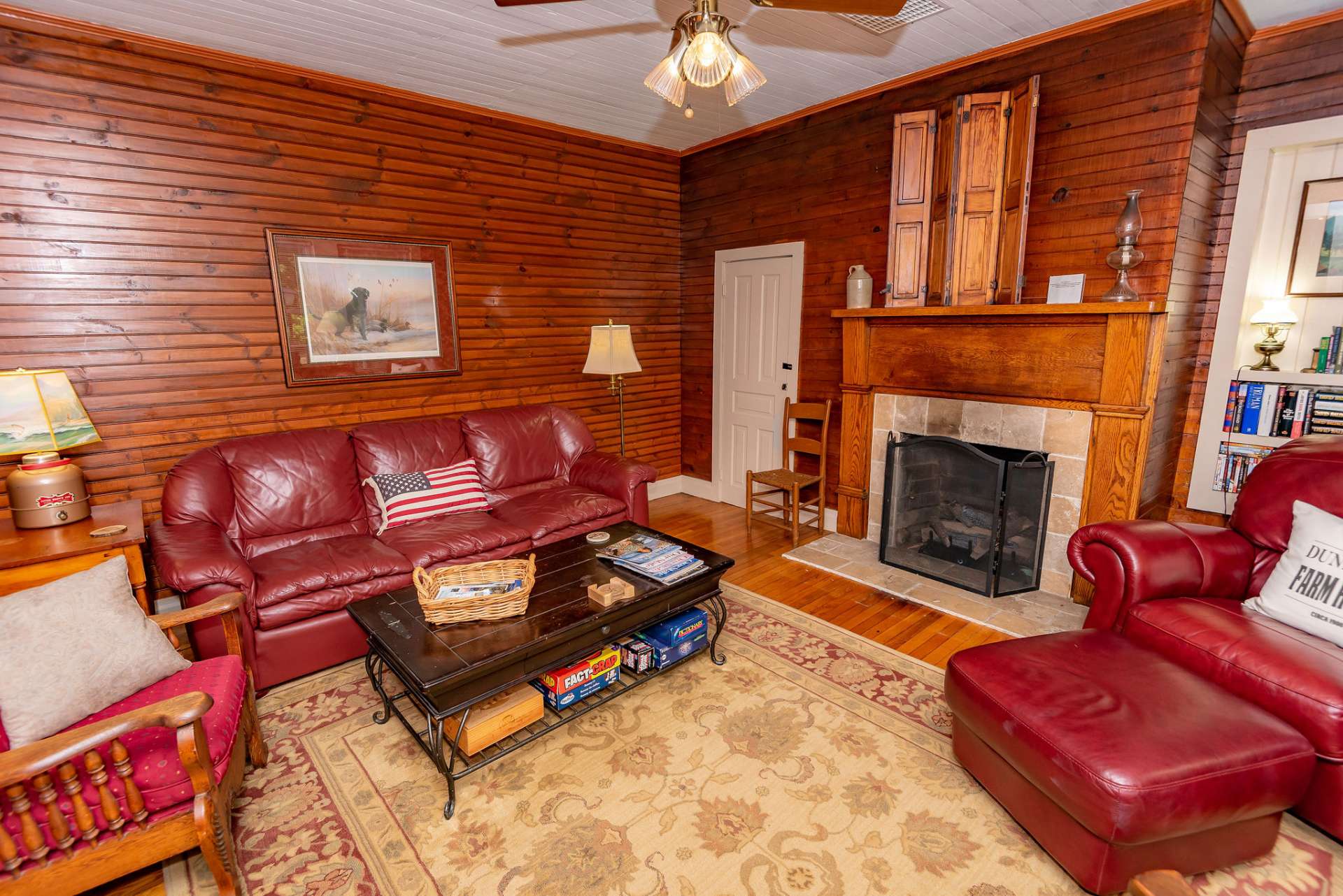 Relax in the cozy living room with original wood floors, beadboard walls, and fireplace with gas logs.