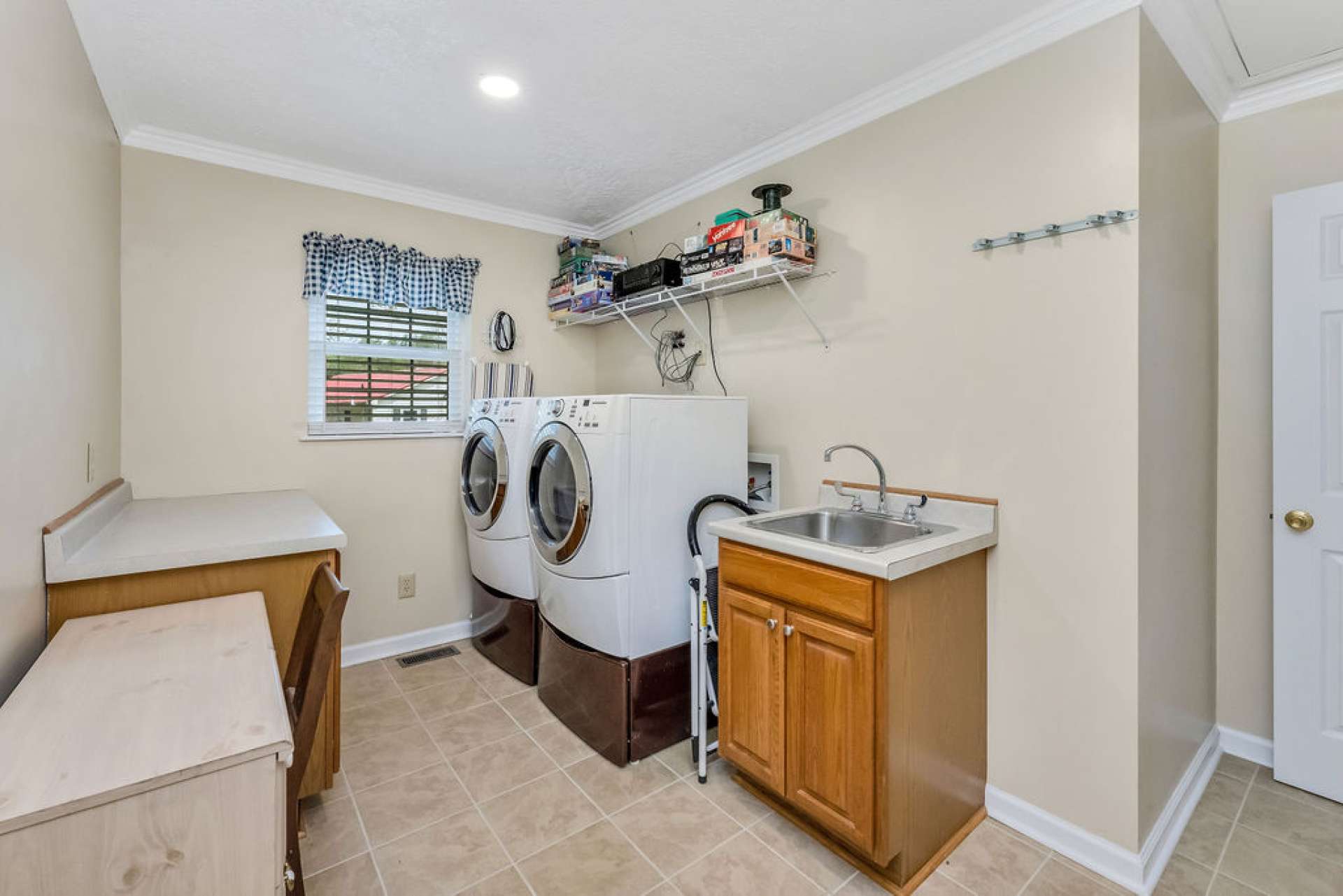 The laundry room is thoughtfully equipped with a folding table, built-in desk, utility sink, and front-loading washer and dryer for added convenience.