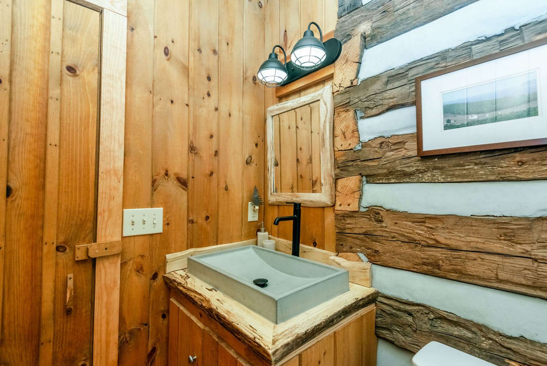 Modern cement sink sits on a custom raw wood countertop.