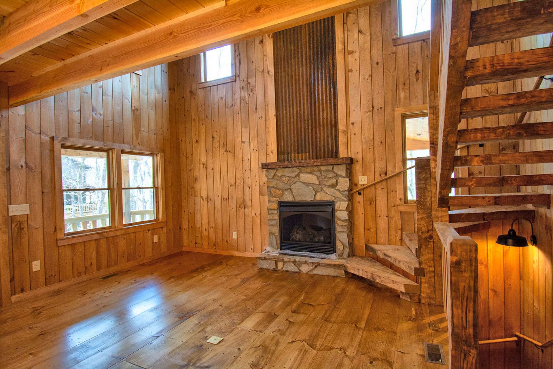 The vaulted great room greets with gleaming wood floors, lots of windows, and a fireplace with gas logs.