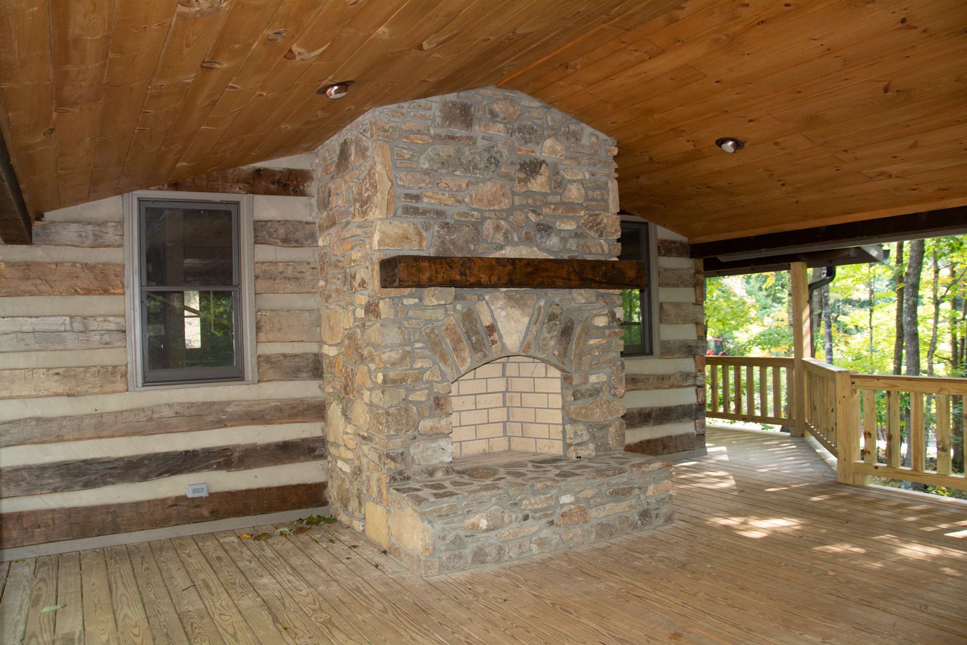 The main level offers a vaulted covered deck area with outdoor stone fireplace to enjoy the views of the surrounding woodlands and the sounds of a bold mountain stream below.