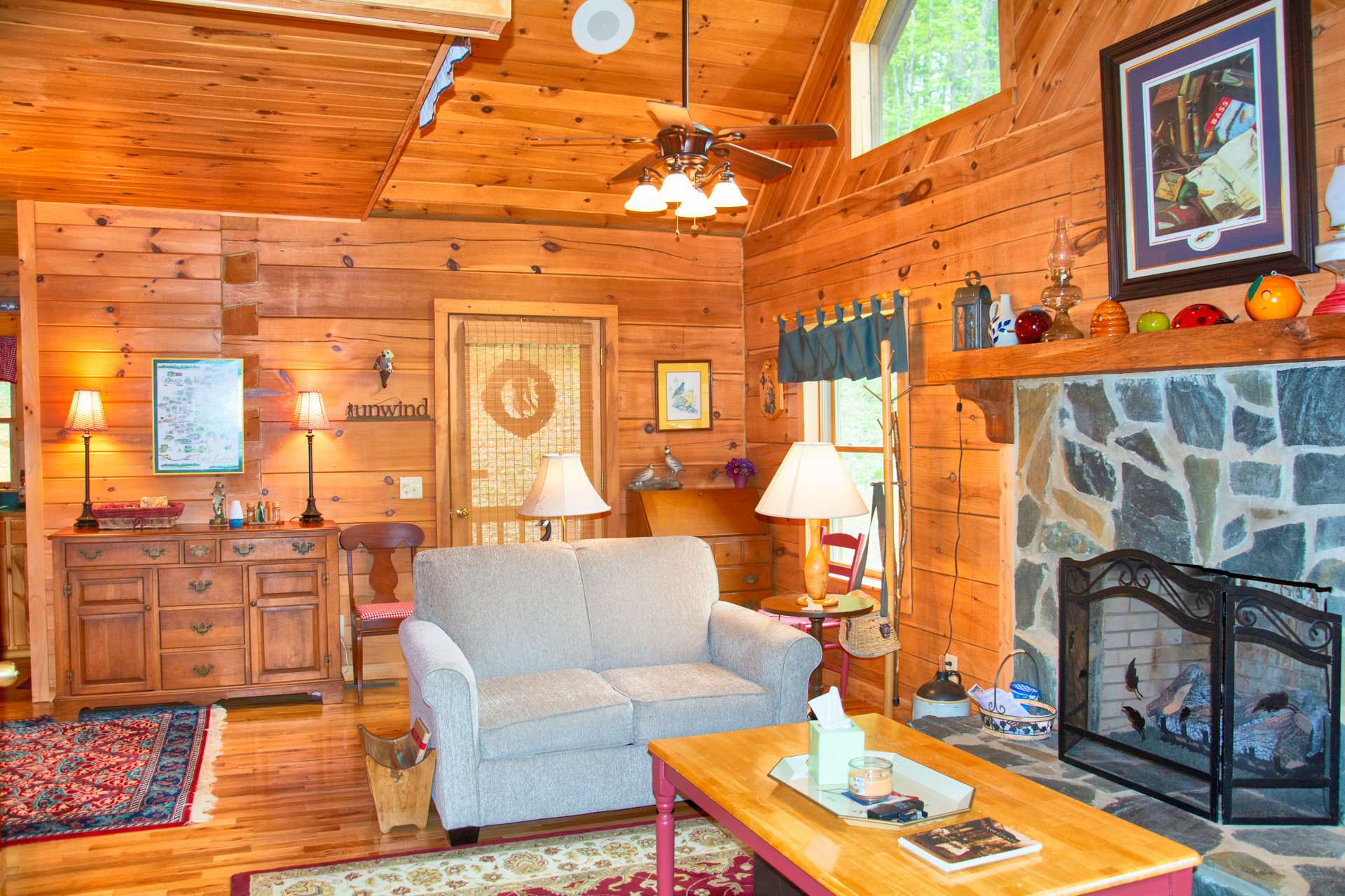 The great room welcomes you with a high vaulted ceiling, wood floors, stone fireplace, and lots of windows filling the cabin with natural light.