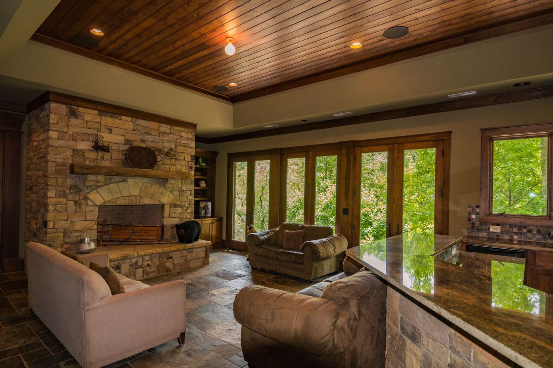 The great room is open and features high ceilings with exposed beams, tall windows to capture the outdoor scenery and natural light, beautiful wood floors, plus a stone fireplace with gas logs to warm up those cool winter evenings.