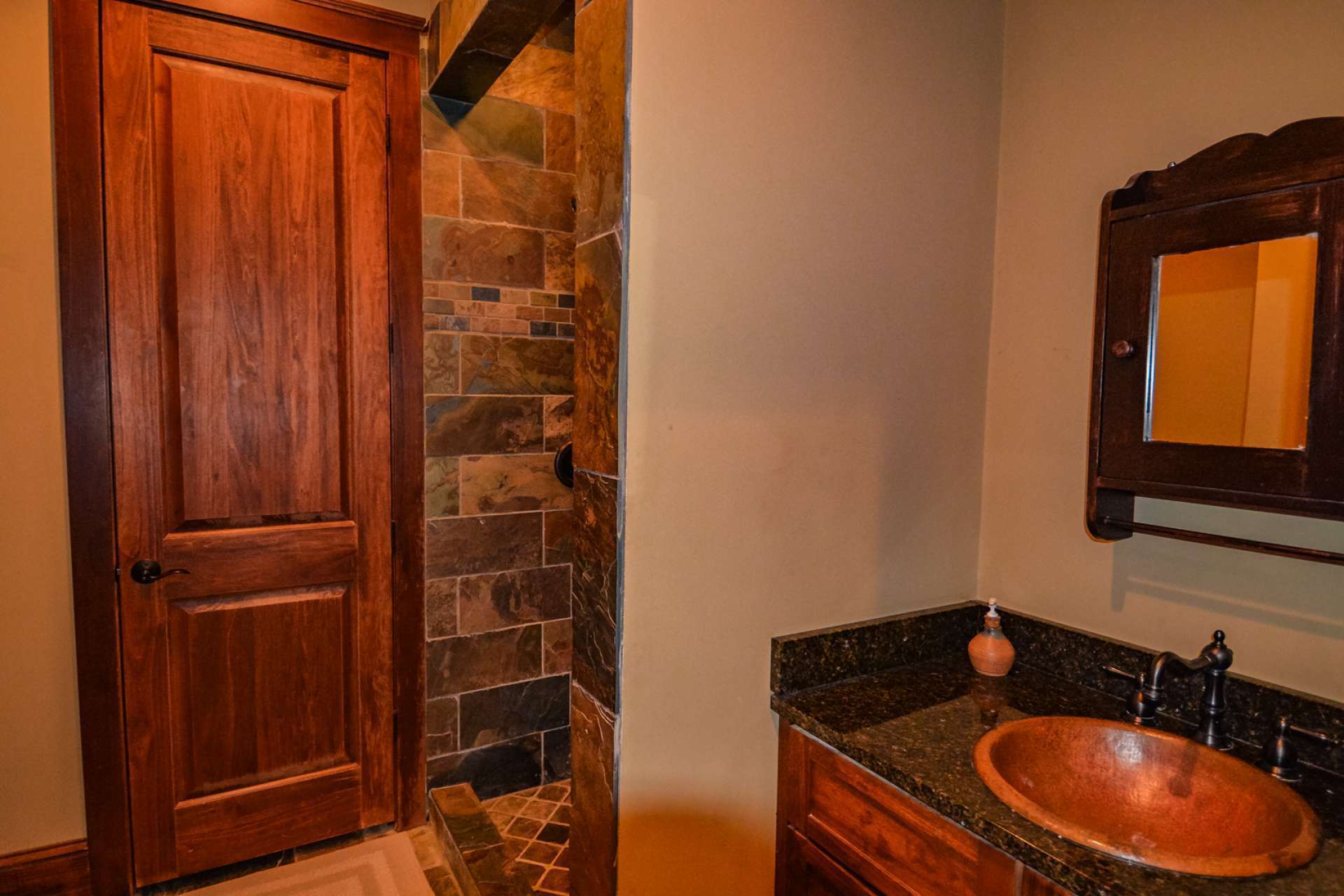 The lower level bathroom has a beautifully tiled shower and a copper sink.