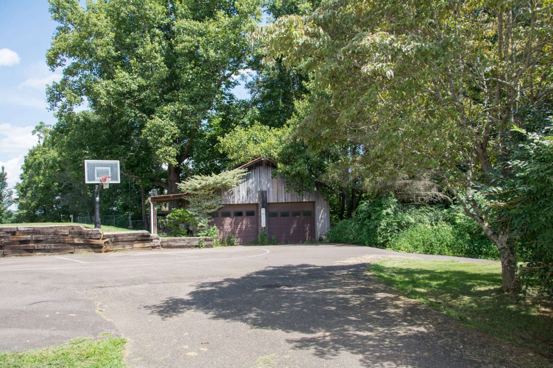 An added bonus is the detached garages, equipment shed, and this paved space that is perfect for parking or basketball.