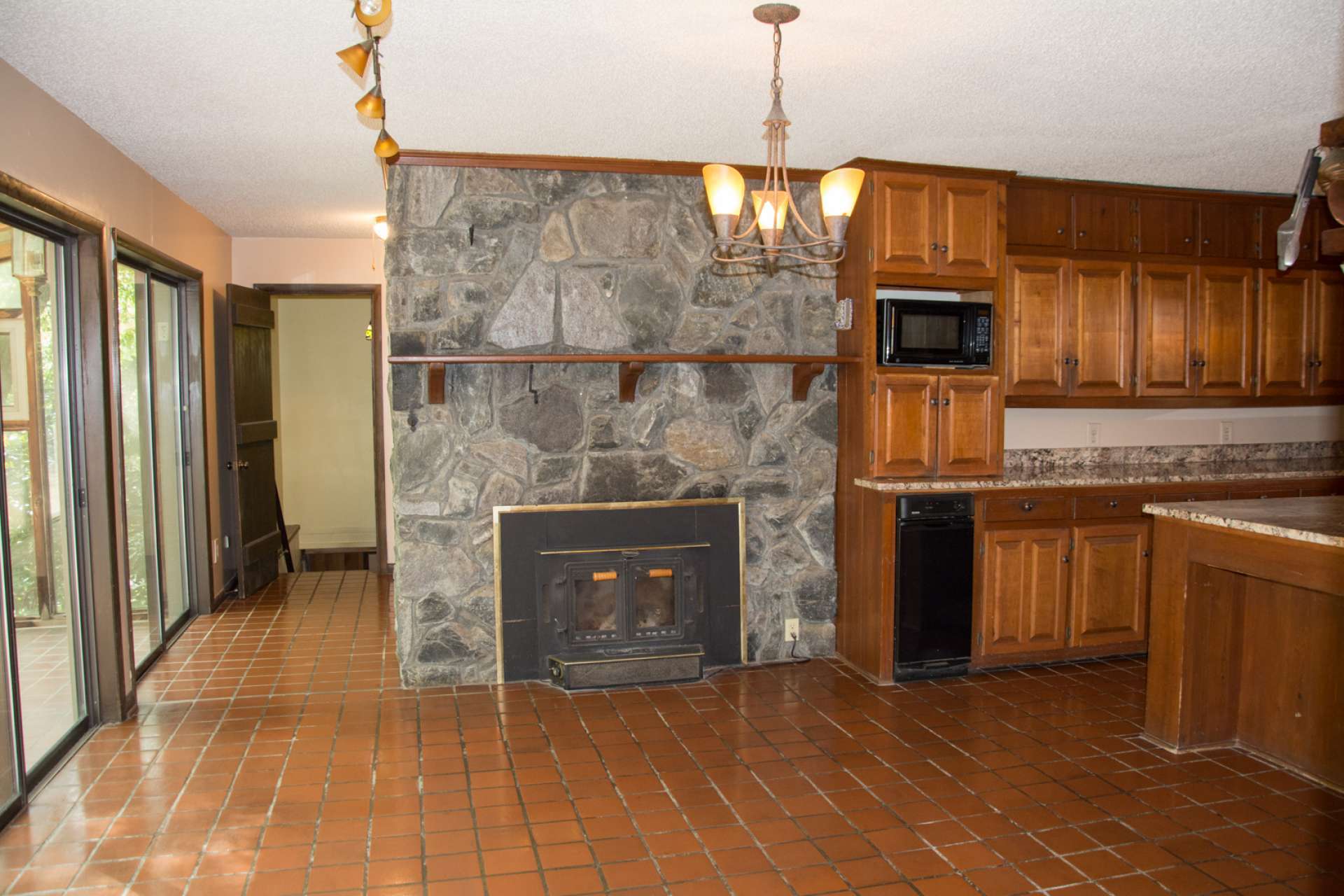 The kitchen is open to an informal dining area featuring a second fireplace with wood stove insert, and lots of glass for natural light.