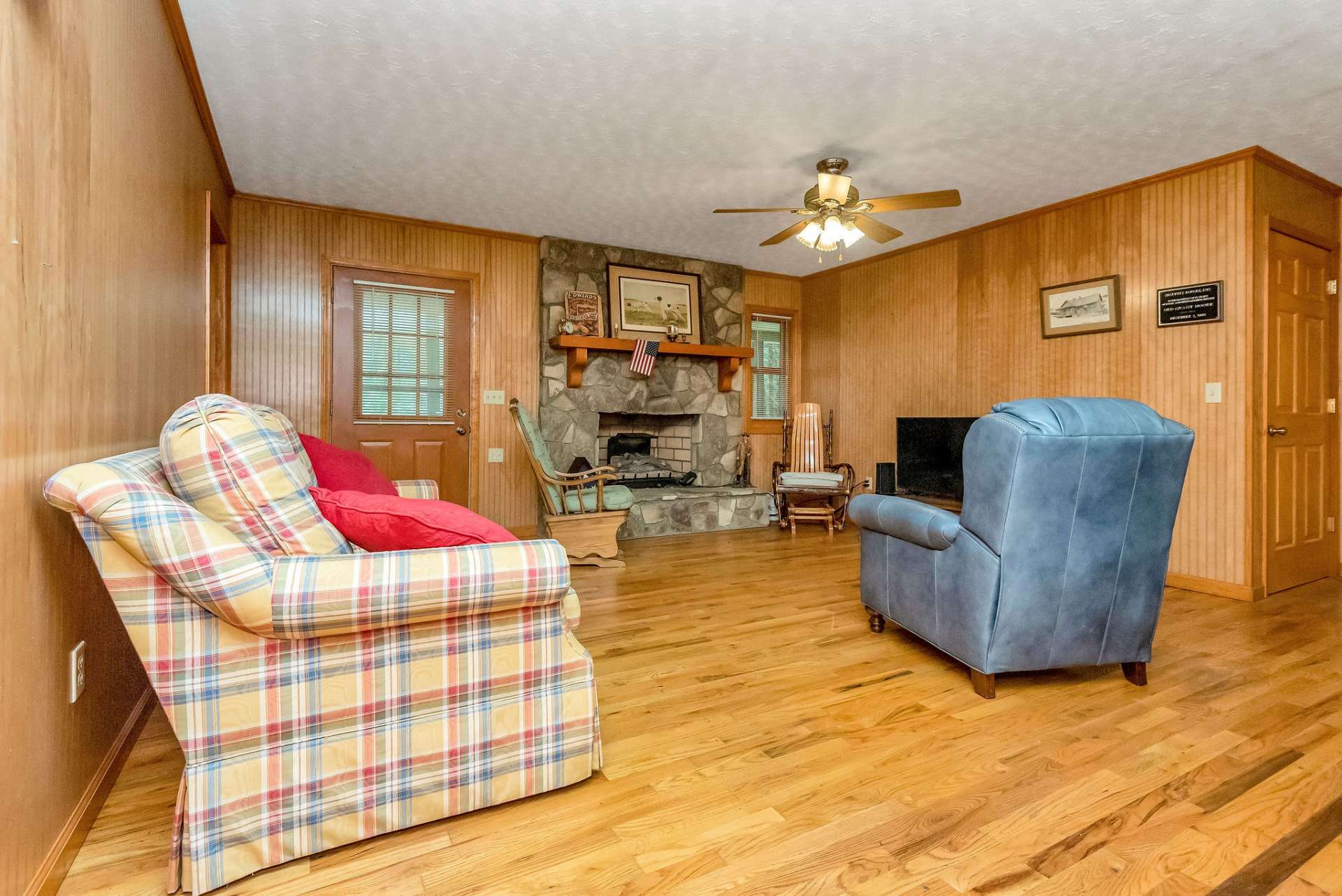 The living area is open to the kitchen and offers a stone fireplace and hardwood floors.