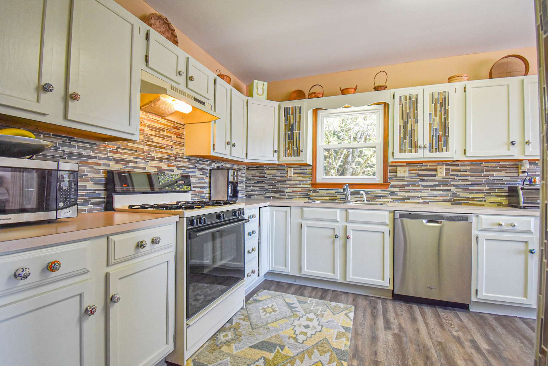 Notice the tiled accents and custom cabinetry hardware. Appliances include refrigerator, gas range, and stainless dishwasher.