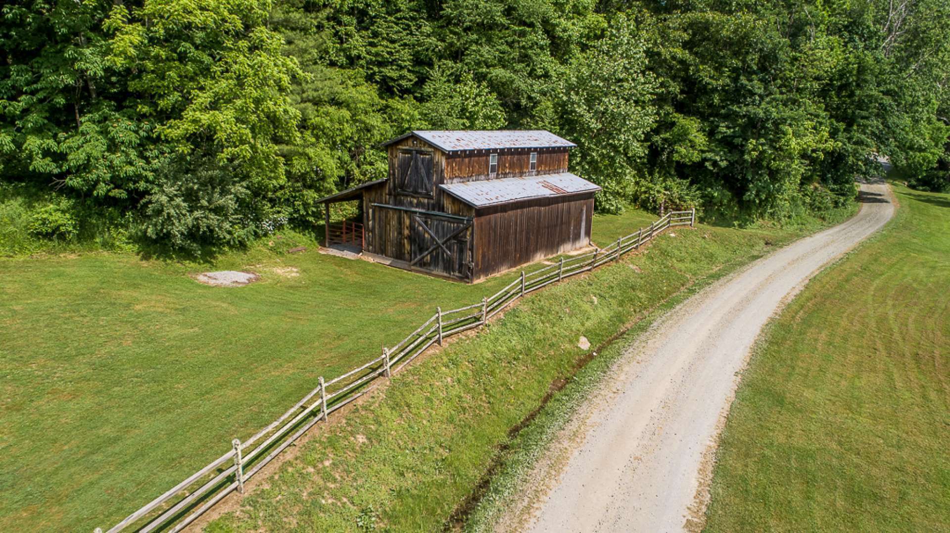 This homestead style hardwood barn features two stalls and plenty of room for equipment or livestock. The wooded areas are great for exploring, too.