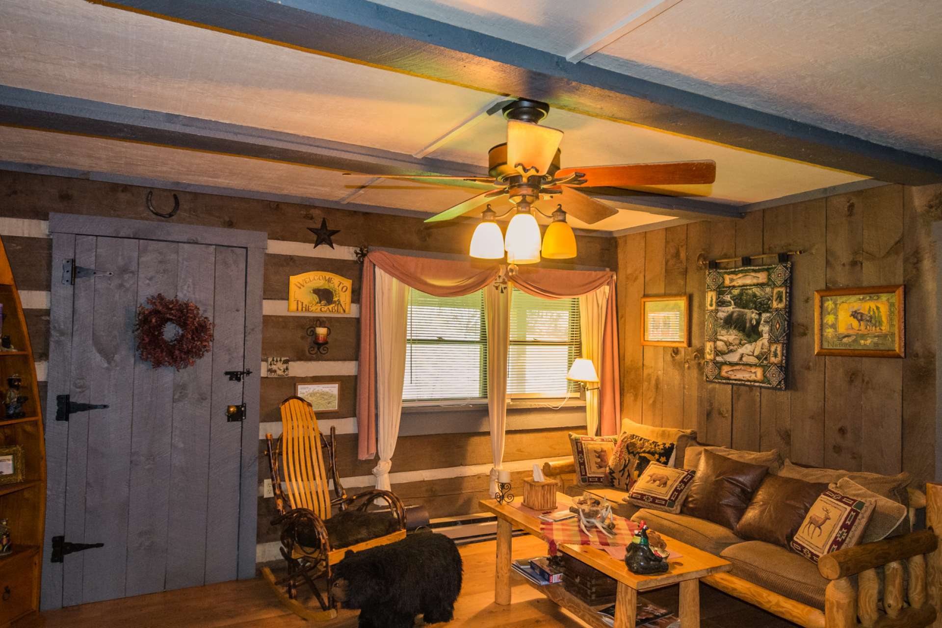 The living room features the rustic feel with a  fireplace with gas logs and walk-out access to the full length covered porch.