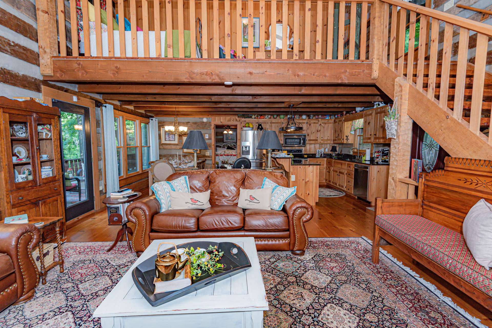 View from the hearth of the fireplace looking toward kitchen and dining area with a peek to the open loft above.