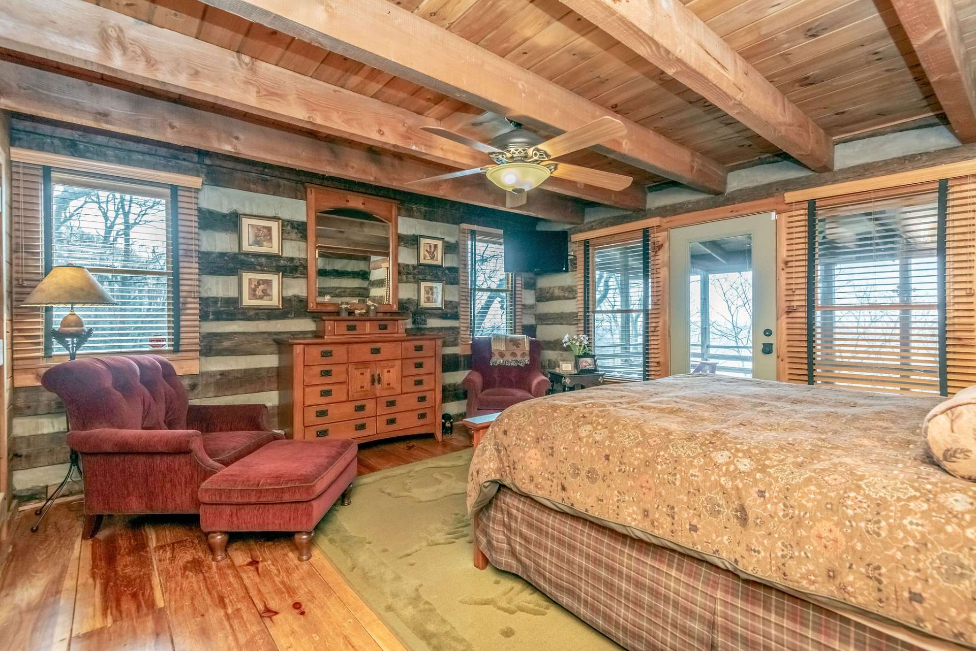 The bedroom is bright and airy with views from the windows and door to covered porch.