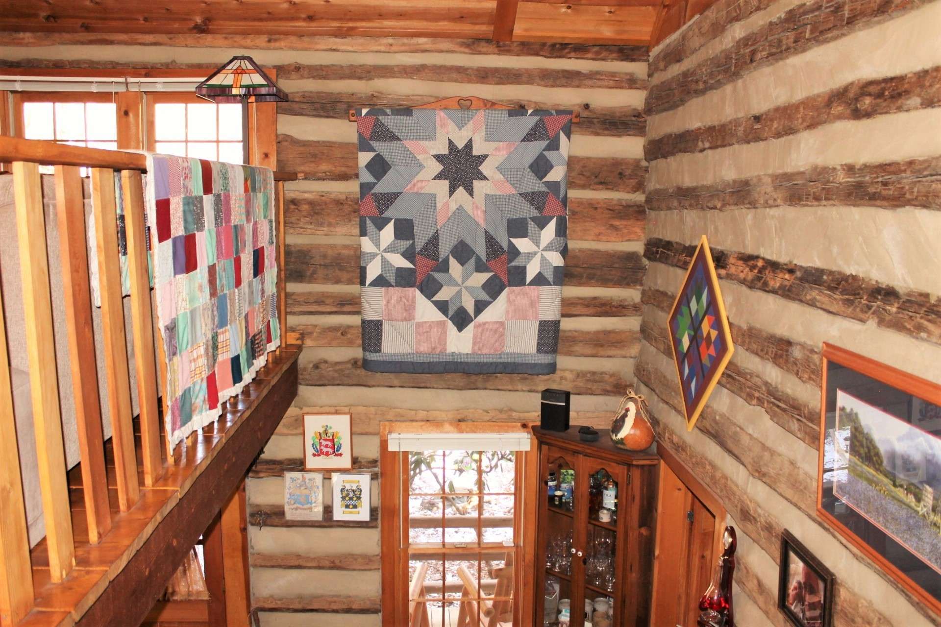 The antique log walls and railings display mountain art and quilts.