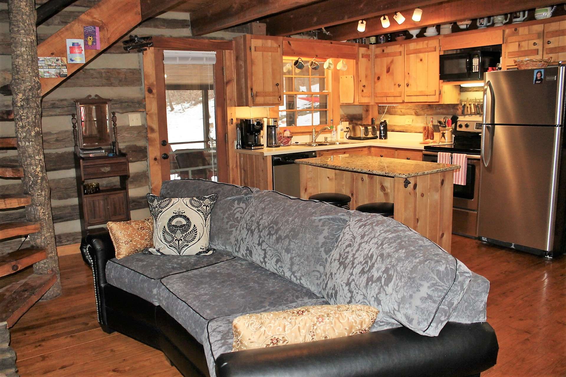 Open floor plan with sitting area, kitchen and dining area with access to covered screen porch in the back. Notice the gleaming wood floors thoughout the cabin.