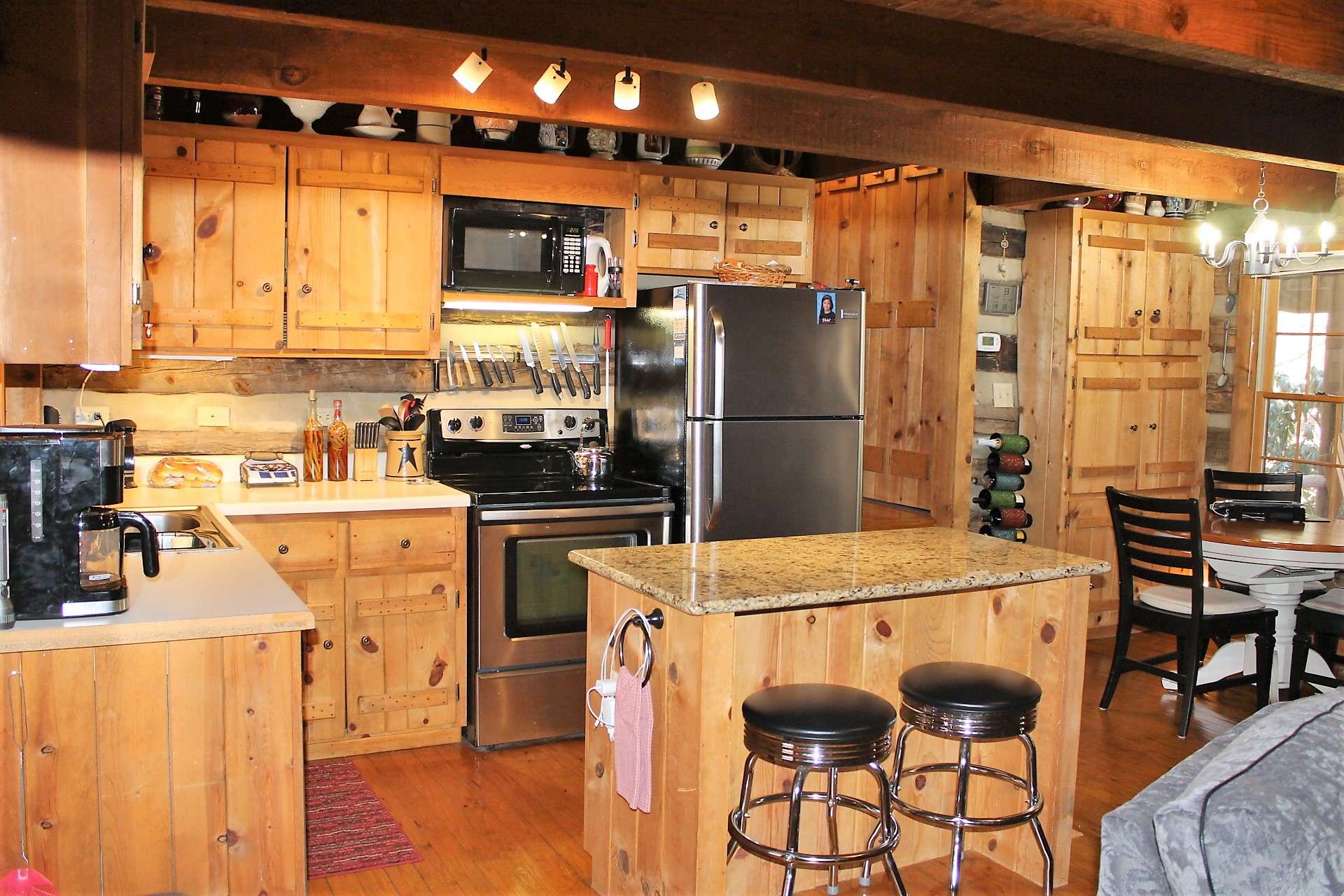 The kitchen with rustic custom cabinets has been updated with an island bar with granite countertop and stainless appliances.