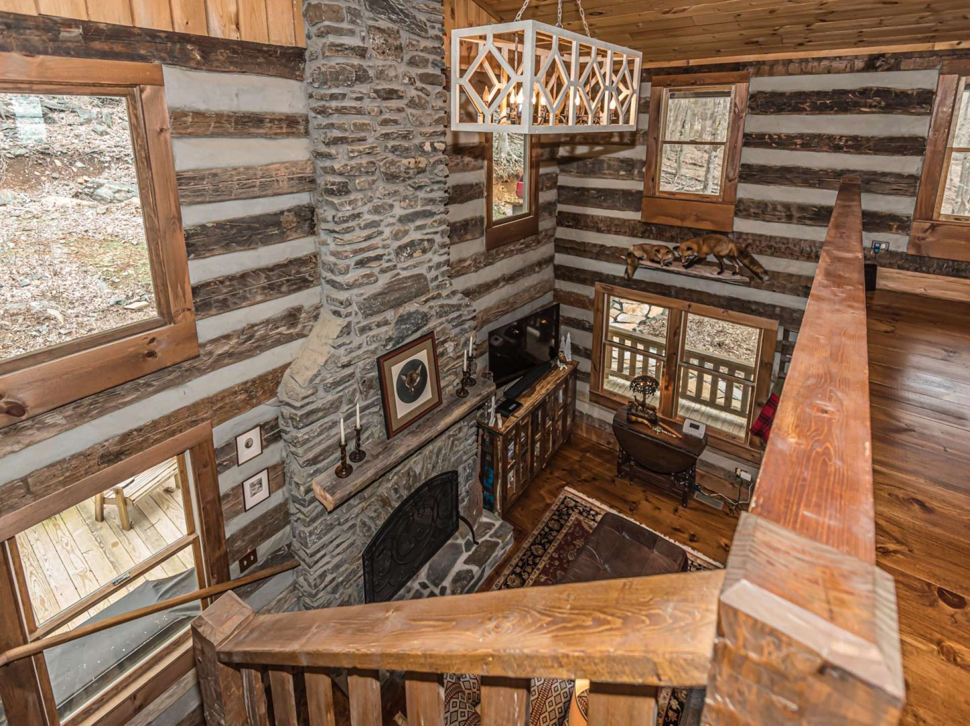 View of the great room from the top of the stairs. Notice the rustic yet elegant lighting provided throughout the cabin.