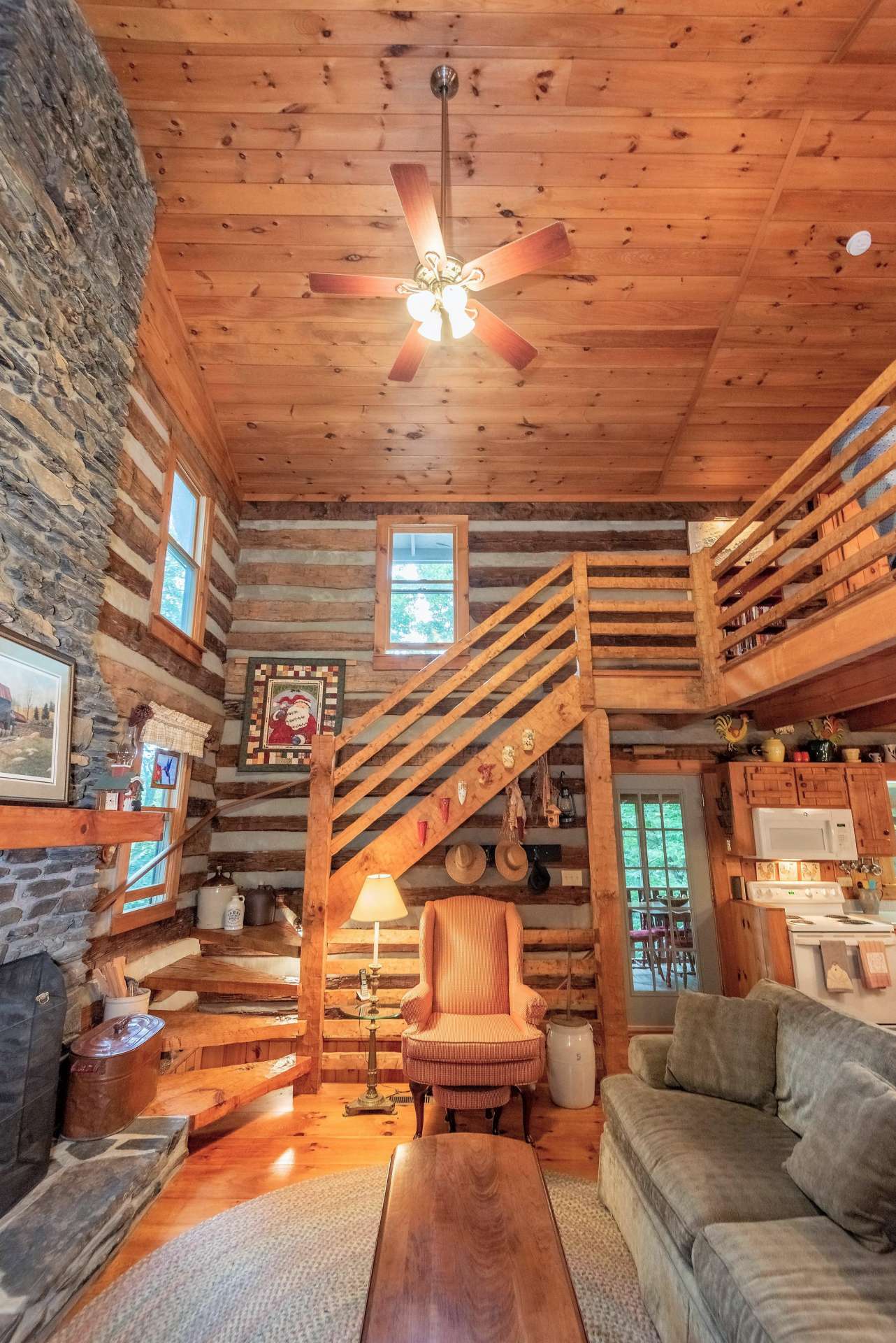 The rustic hand-hewn staircase leads up to the loft area and also leads down to a finished lower level.