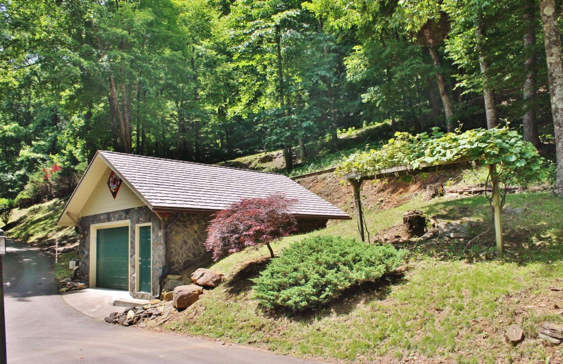 A quiet road, canopied with native mountain laurel and hardwoods, leads to the paved driveway with detached garage and lovely landscaped entrance.