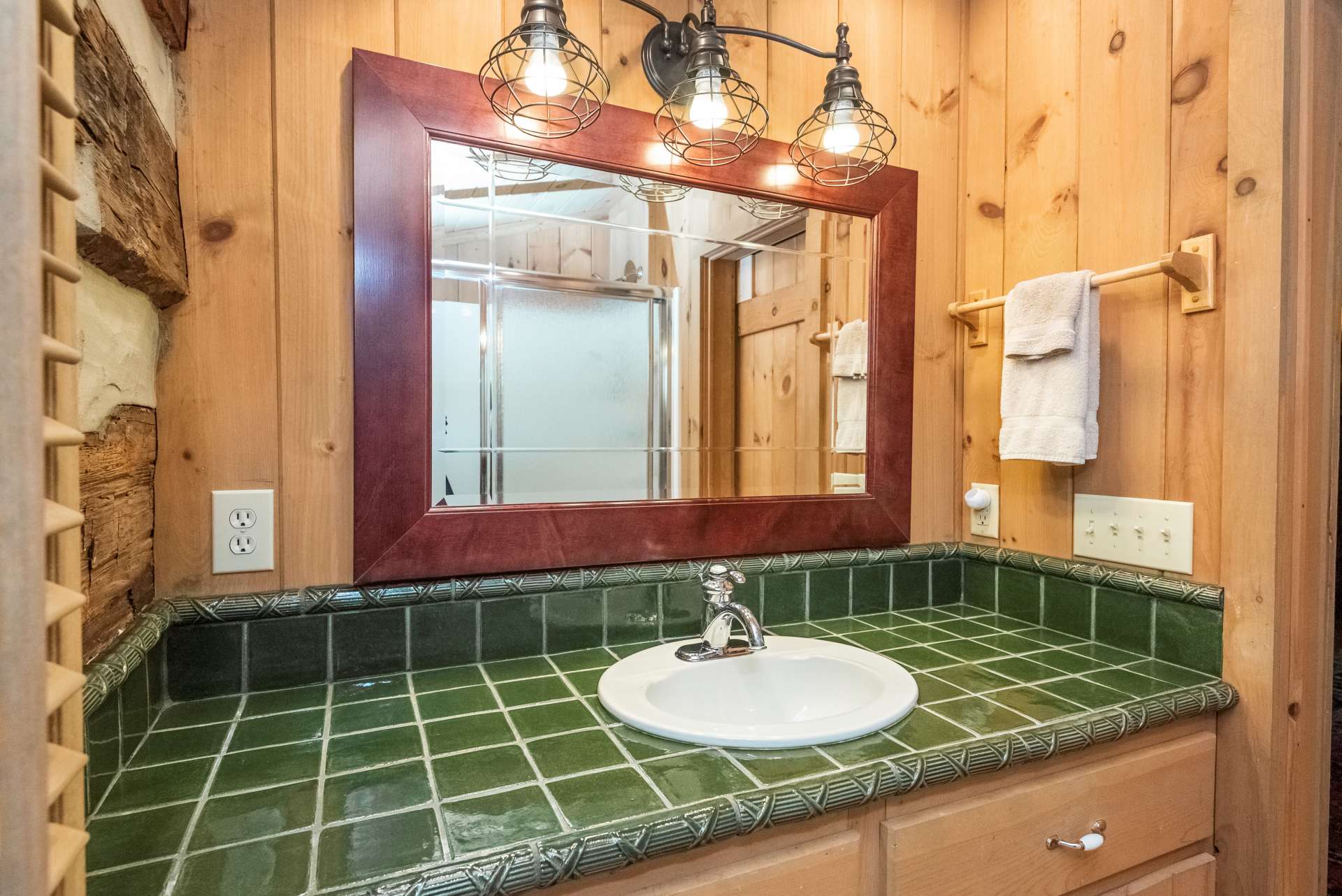 Unique green tile sinks and modern lighting carry continuity throughout the home.