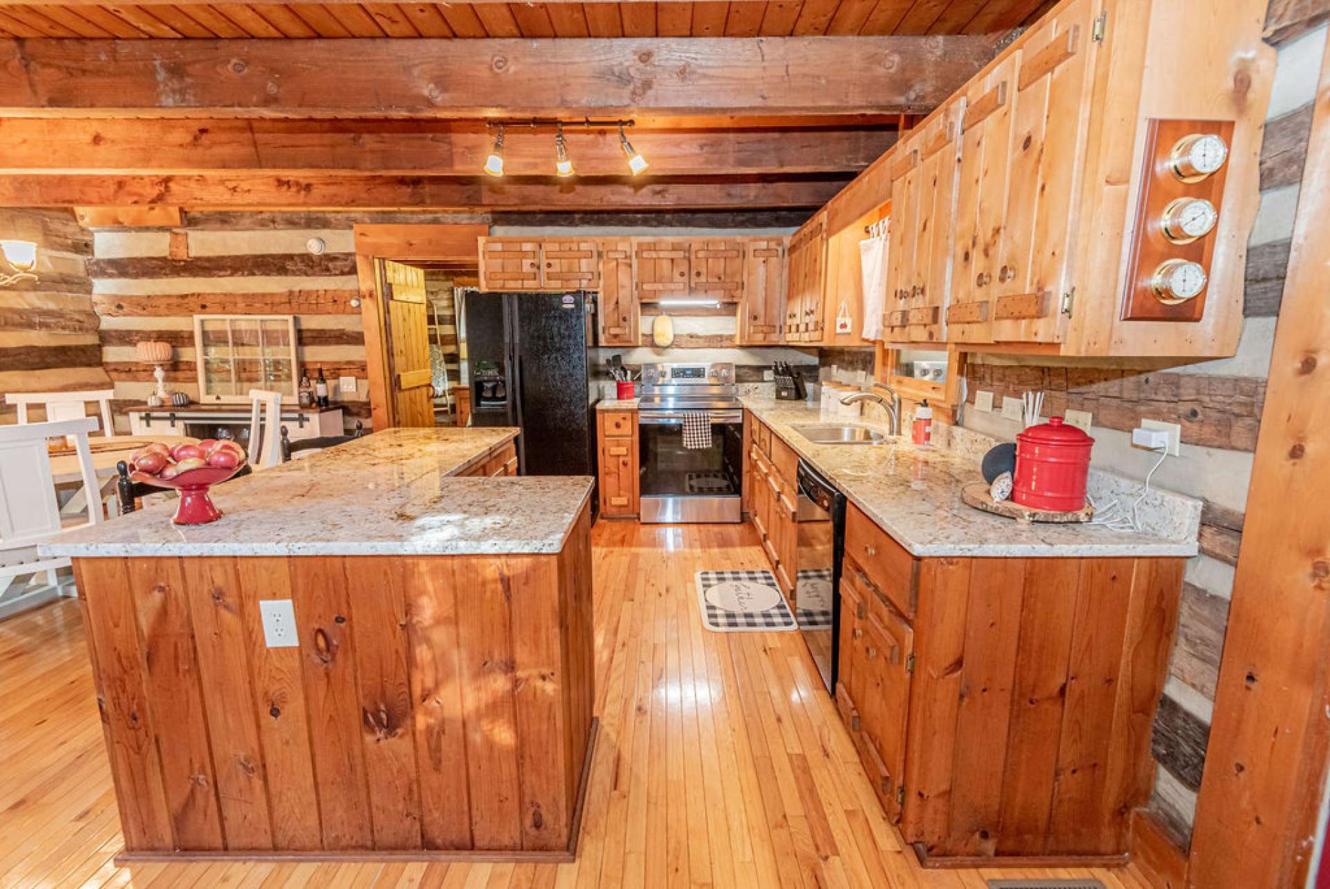 This kitchen has modern appliances, impressive granite countertops, and exposed beams to enhance the log cabin feel.