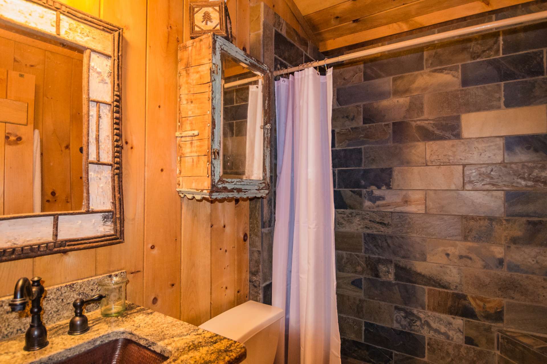 The main level full bath features a one-of-a-kind wormy chestnut vanity with copper sink and granite top, and a tiled walk-in shower. The laundry closet is also located on the main level.
