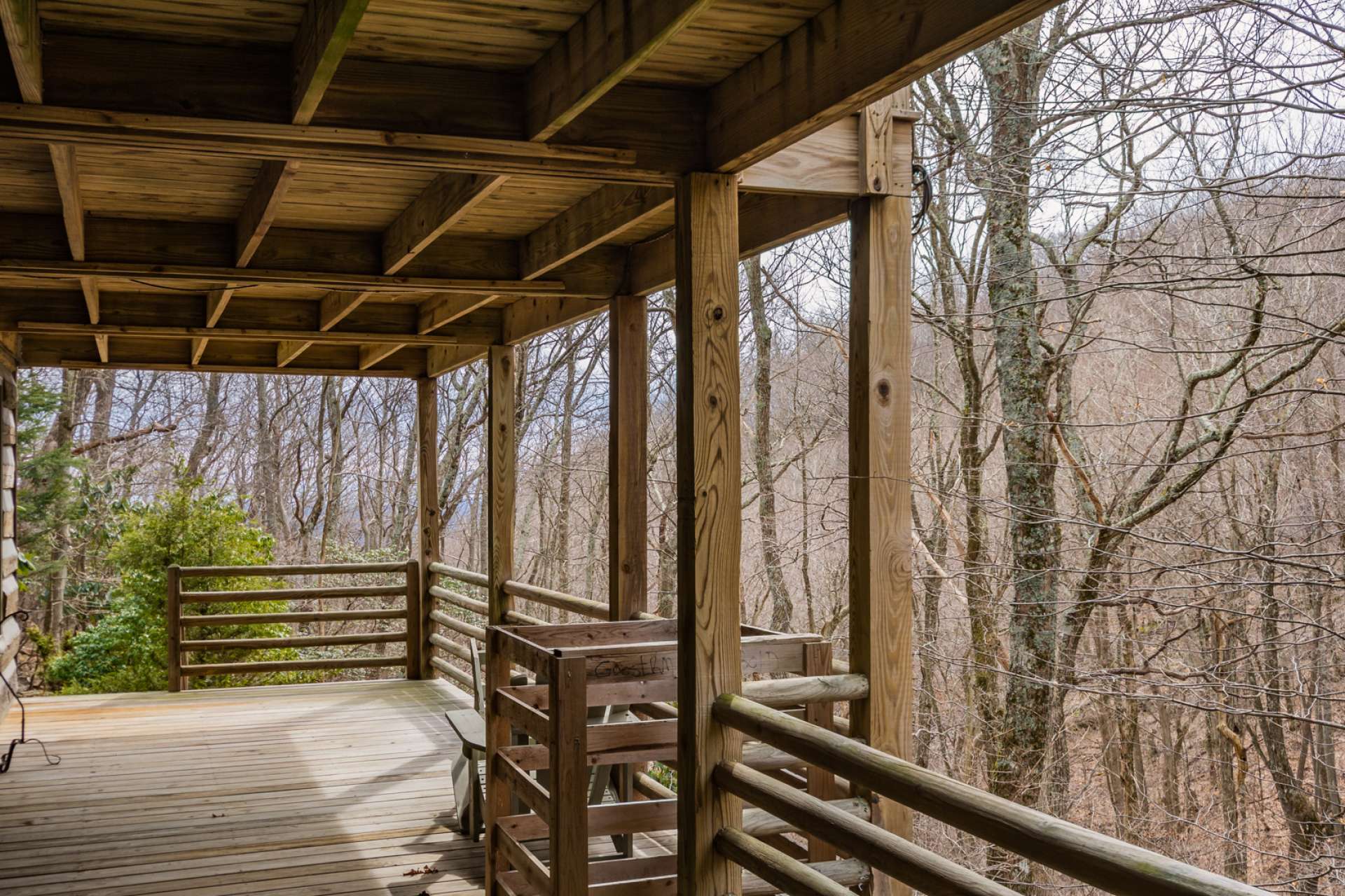 The lower level deck expands the outdoor living space and overlooks the woodlands with a rushing mountain creek.