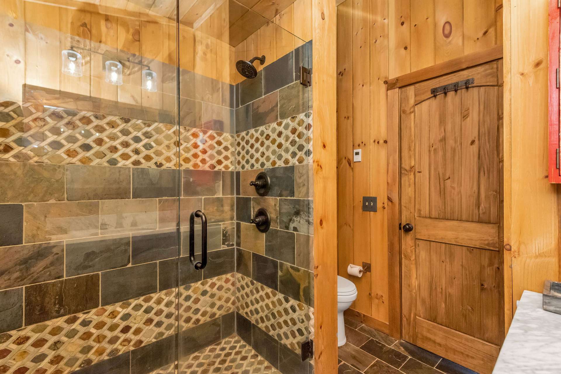 Pamper yourself in the primary bath's uniquely designed walk-in slate tile shower with glass doors.