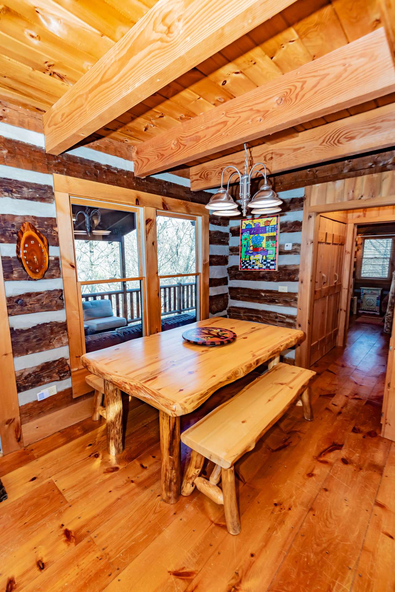 The rustic dining table with bench seating has views to the covered deck just steps away.