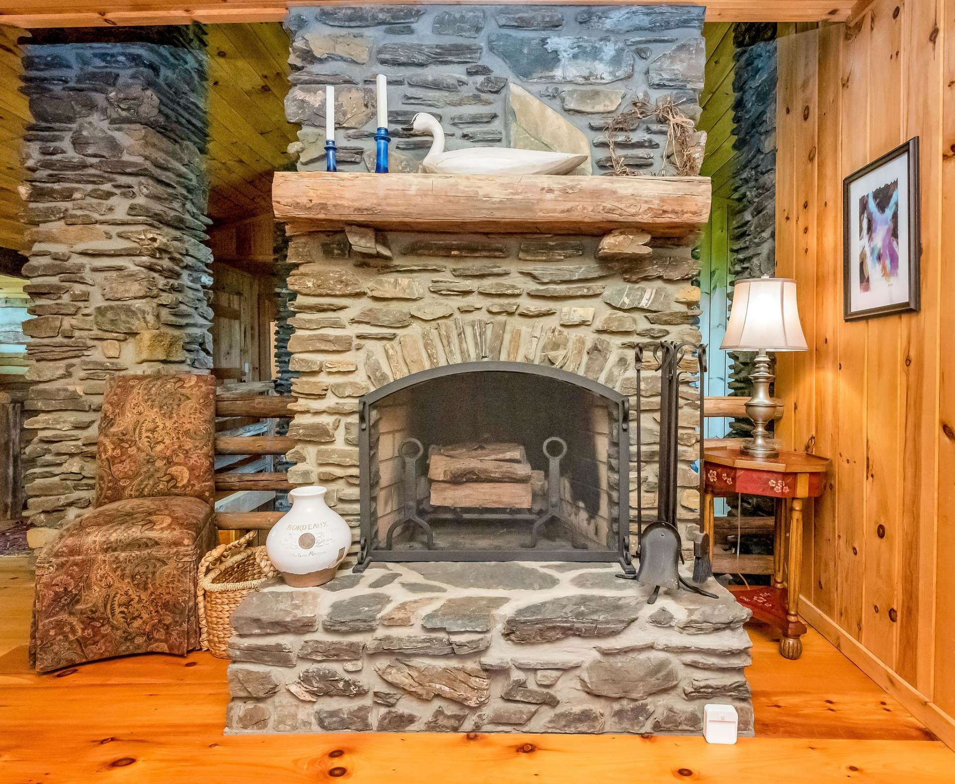 Sitting area is accentuated by another stone, wood-burning fireplace.