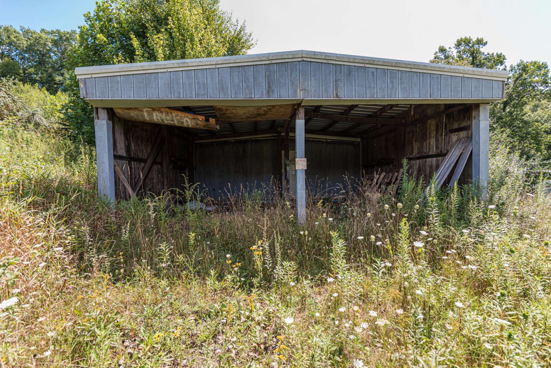 This building has a concrete floor and a greenhouse on one end and a run in shed on the other end.