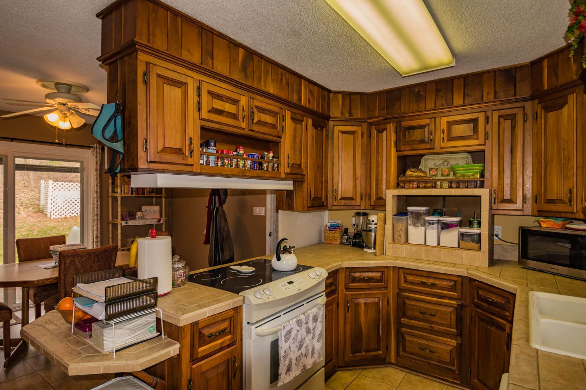 The galley style kitchen features walnut cabinets, ceramic tile flooring, newer appliances, and lots of work and storage space