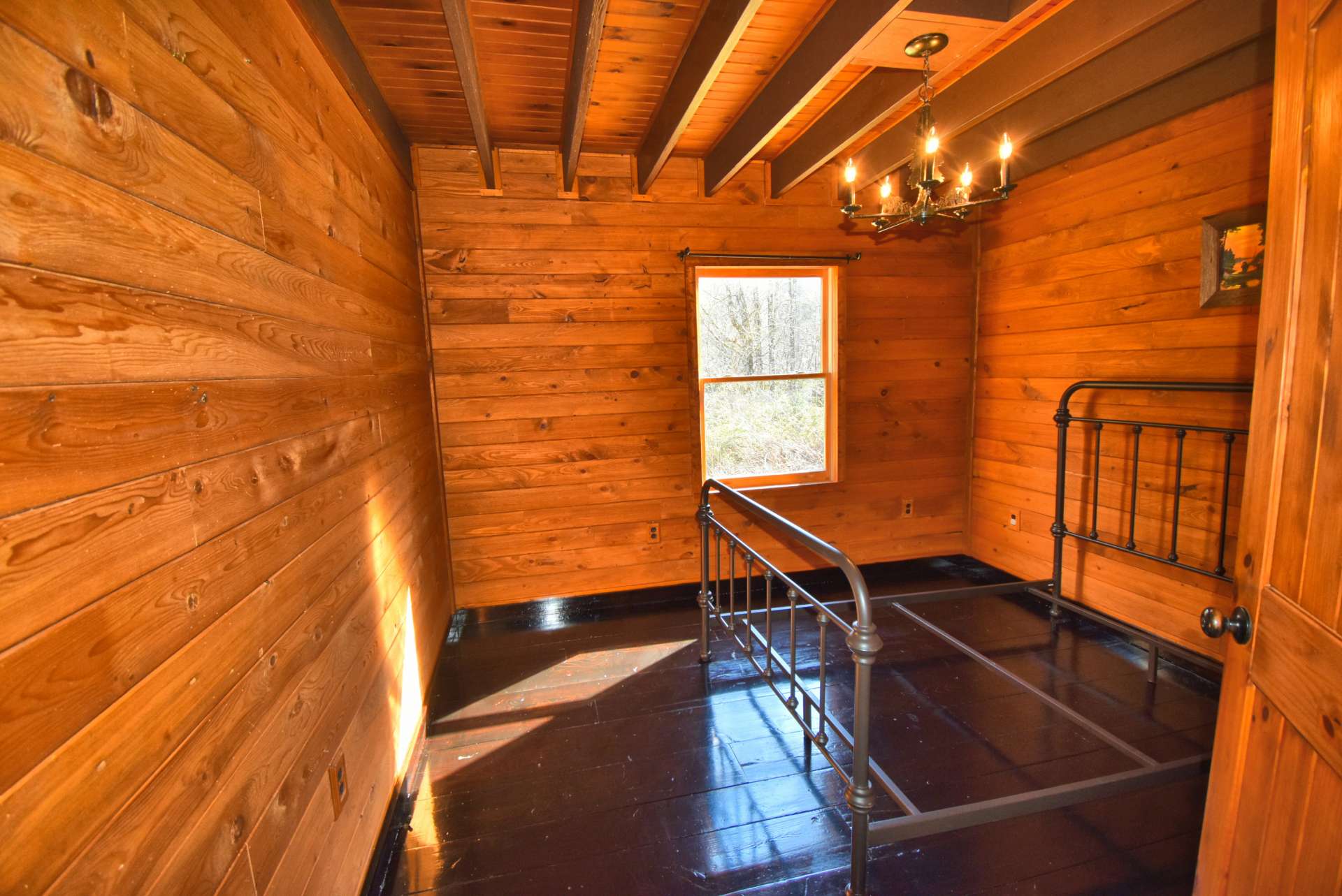 This is the main level  bedroom.  Notice exposed beams throughout the cabin. Wide plank wood floors in the great room and bedrooms.