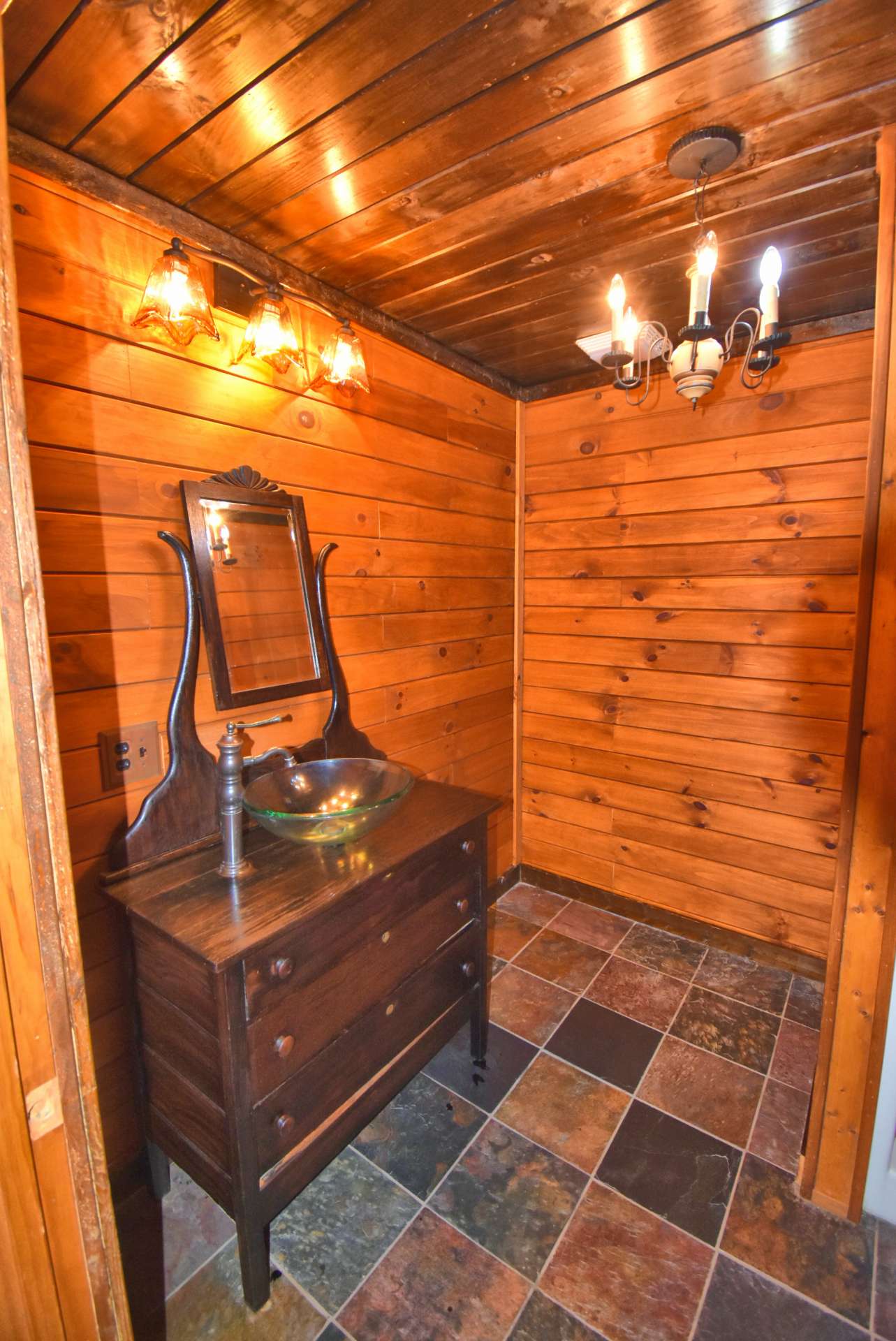 A spacious main level bath offers more custom details including tiled floor and walk-in shower.